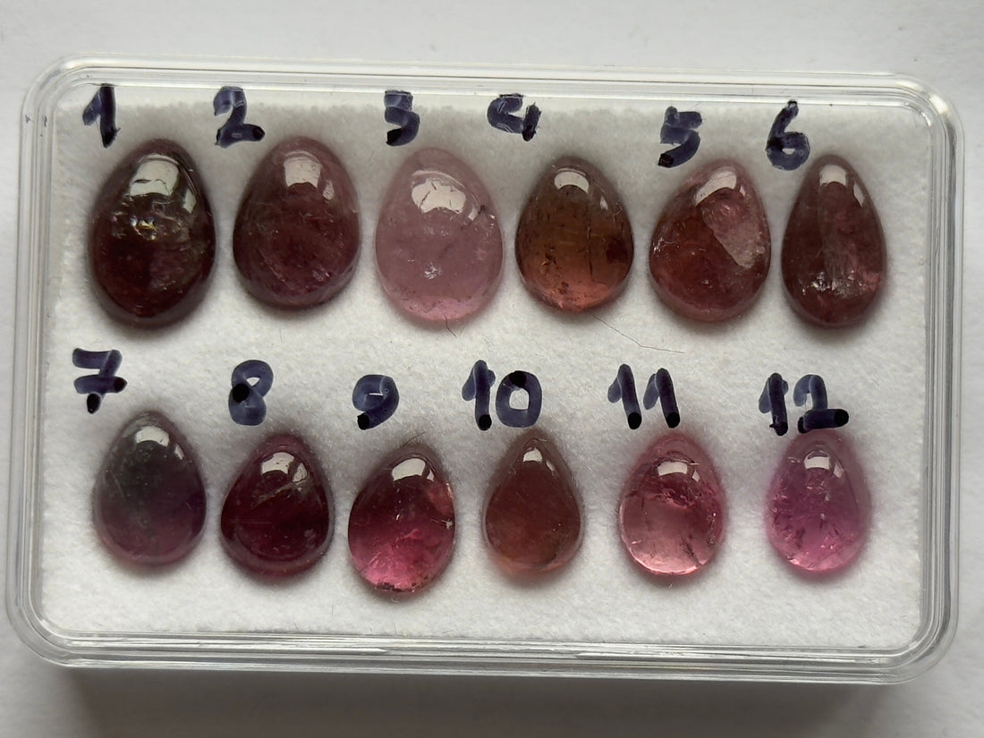 Pink tourmaline pear-shaped cabochons laid out for comparison