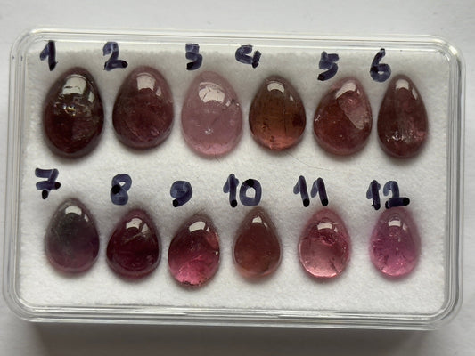 Pink tourmaline pear-shaped cabochons laid out for comparison