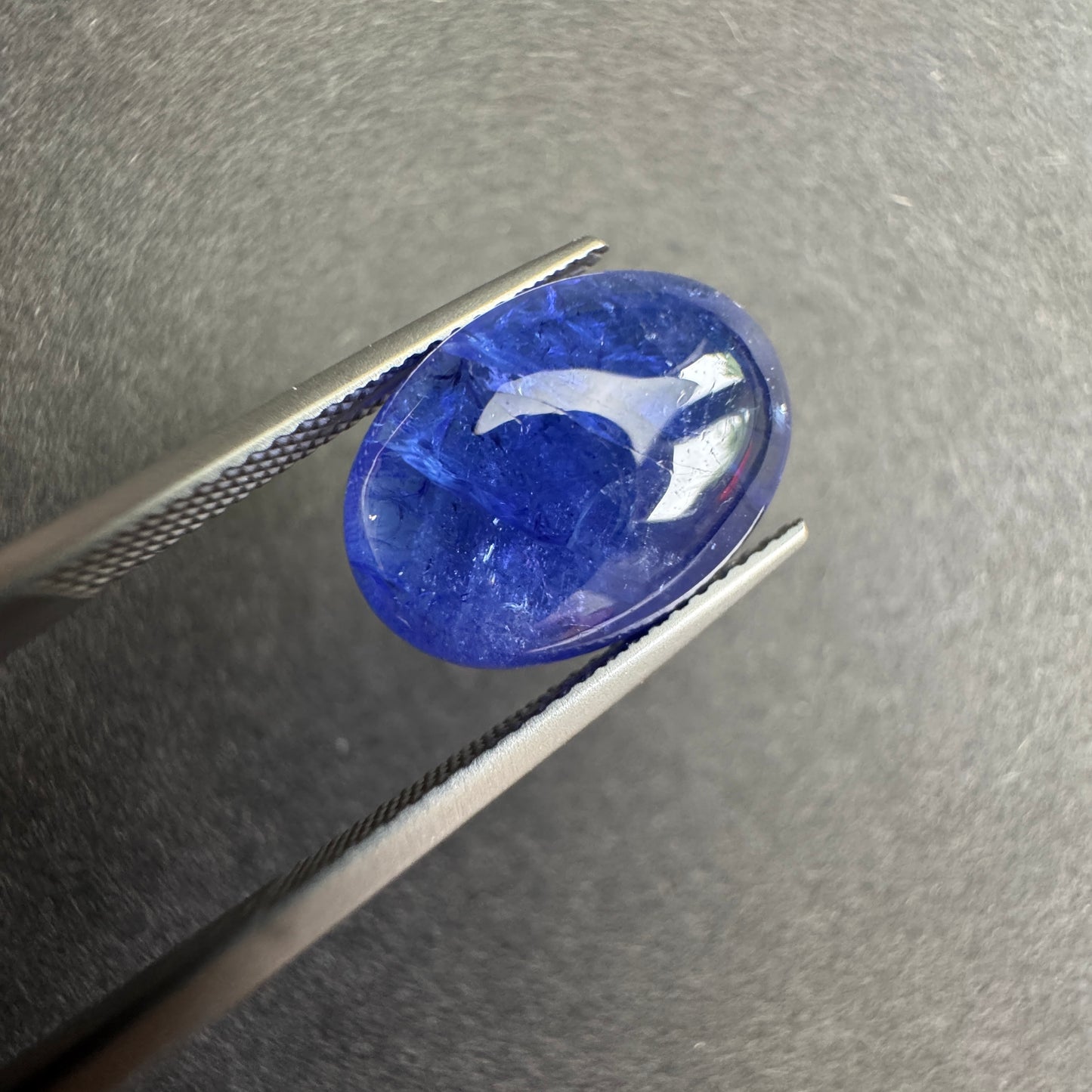 a captivating deep indigo blue oval shape with subtle white inclusions.