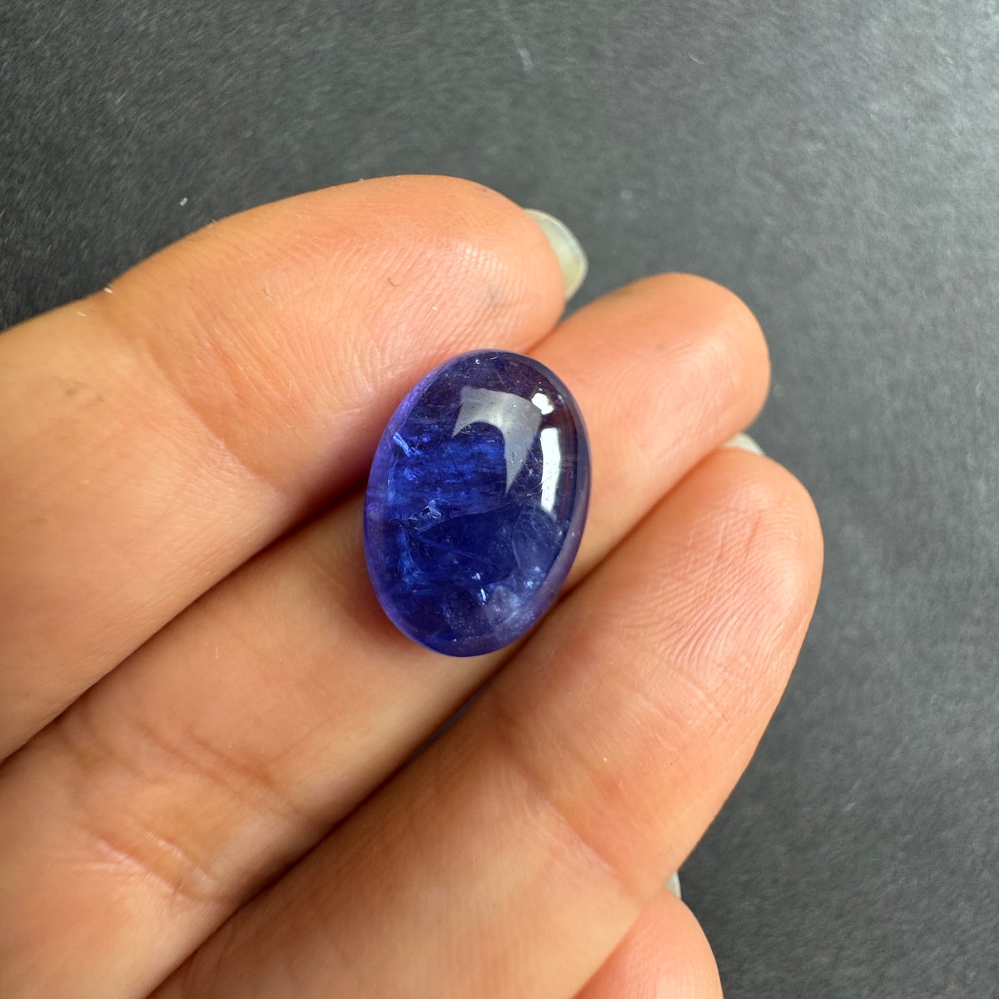 a captivating deep indigo blue oval shape with subtle white inclusions.